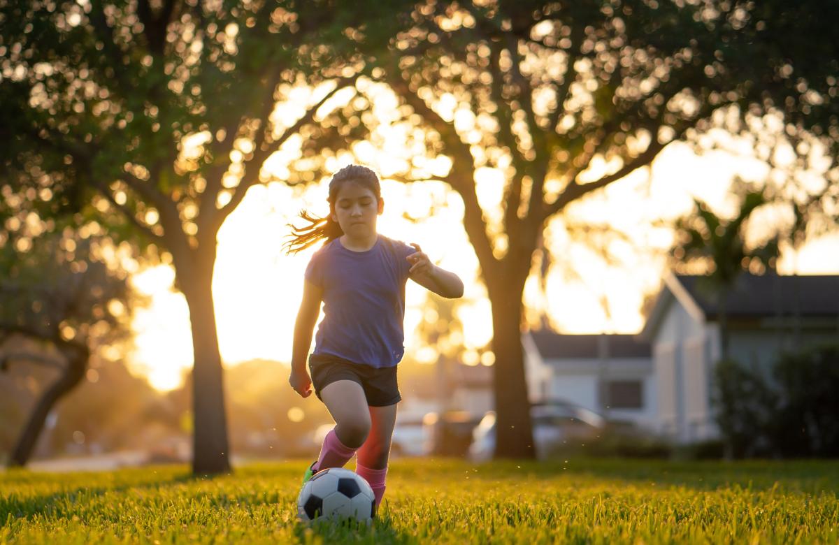Young child playing soccer outside