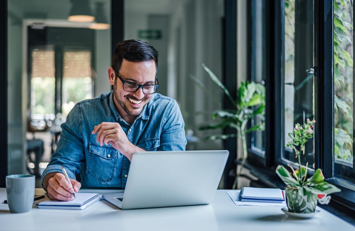 A man sitting at his laptop taking notes