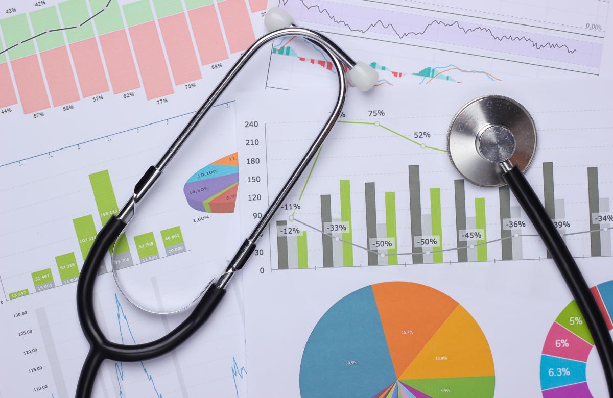 A photo of a stethoscope over sheets of paper with different charts and graphs